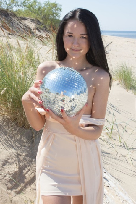 At the beach, Olivia is a brunette who was helped by her friends to hold her bald face while playing at a disco ball.