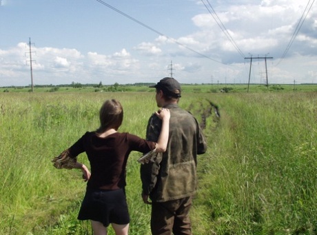 A white girl has a sexual encounter with an army man who is homeless in the privacy of long grasses.