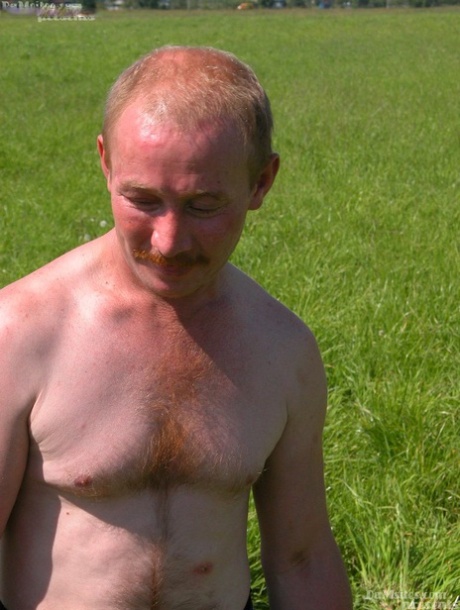 In a field, a man with a red hair engages in sexual activity with a homeless person.