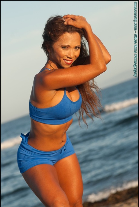 In a beach setting, Cassandra Debois, an Asian fitness model, poses by herself.