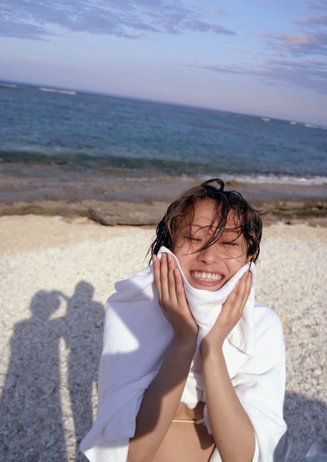 A Japanese model named Nao Yoshizaki is seen dipping her body into the water while hanging out on the beach.