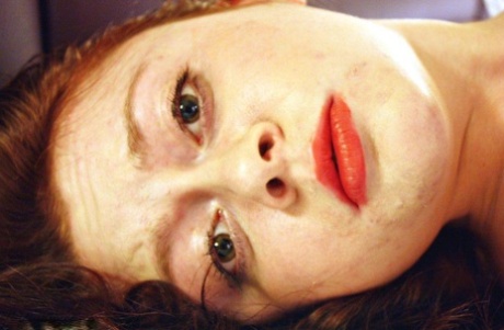 A natural redhead is seen cleaving while being restrained in her clothes on a bed.