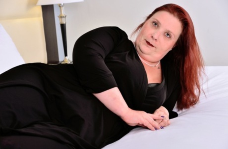 Nikki Hayze, a Canadian redhead who is elderly, exposes her plump body on a bed.