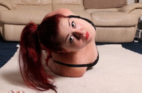 Thick redhead is hogtied in her lingerie while sporting a big ball gag