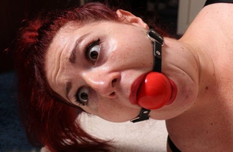 Hogtieing the lingerie of this thick redhead, who is sporting a big ball gag, has never been done before.