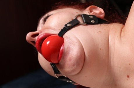 An inch-thick redhead is caught in her lingerie and sporting the big ball gag.