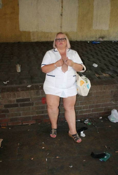 While walking on the sidewalk, Lexie Cummings, a fat and elderly nurse, takes a naked selfie.