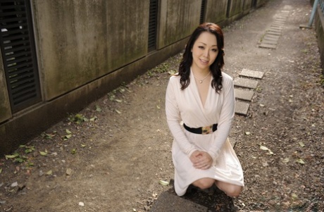 A white dress is worn by Yuna Yamami, a stylish Japanese female, outside in a showy appearance.