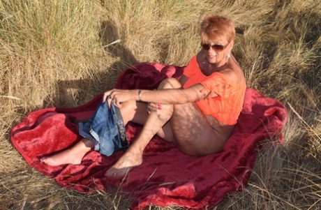 Adorable older woman Dimonty displays big natural wonders on a blanket that overlooks the ocean.