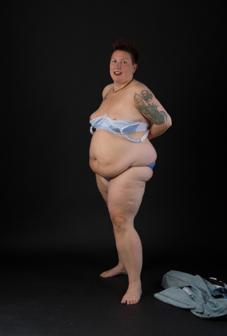 The overweight tattoo woman who is a tattoo artist holds her chest in her hands after taking off her clothes.