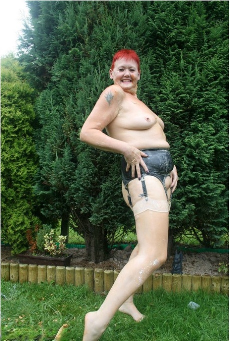 A picture of redhead granny Valgasmic Exposed with nylons on her body is taken in a yard.