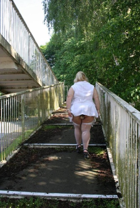 A pedestrian overpass is crossed by Lexie Cummings, a fat blonde who appears to be covering her body.