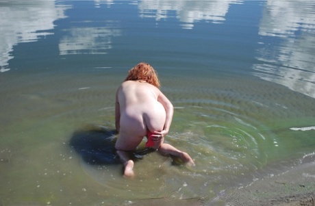 Adorned: Red-headed amateur Misha dips into the mud with her big legs while swimming in shallow water.