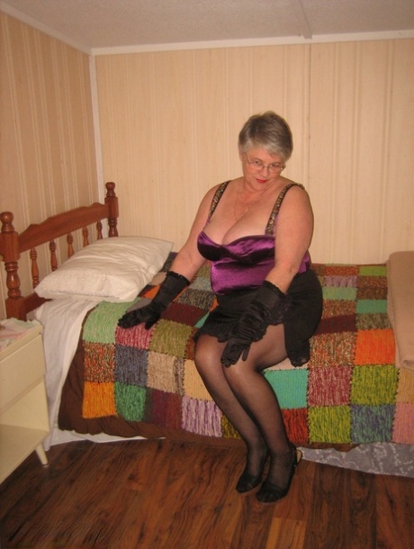 Dark-haired Girdle Goddess, a very popular old fat girdle, is seen getting naked in her bedroom while wearing black gloves.