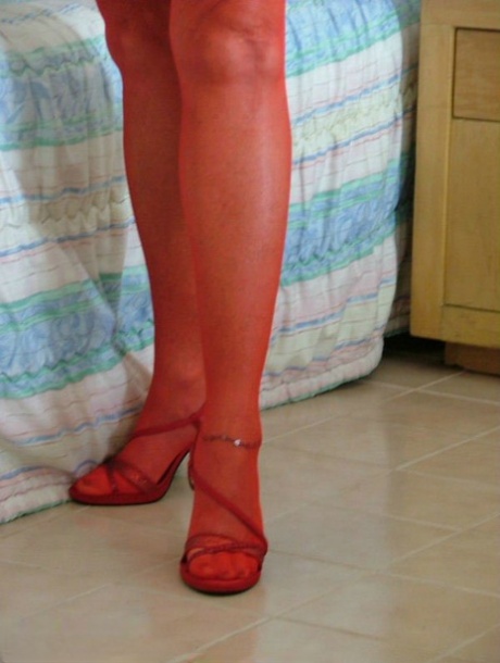 A mature woman who is blonde and wears red lingerie and hosiery has her vibrator stimulated after she masturbates.