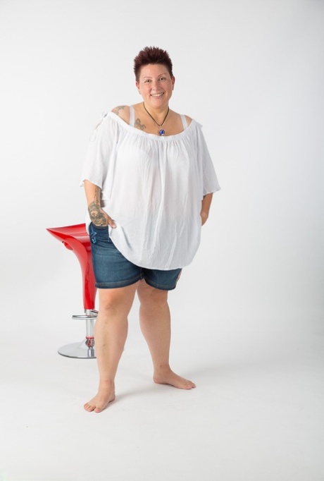 Seated on a stool, the obese amateur Tattoo Girl gets completely nude.