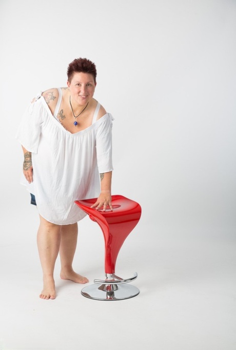The elderly Tattoo Girl who is an amateur takes a seat on a stool after getting completely nude.