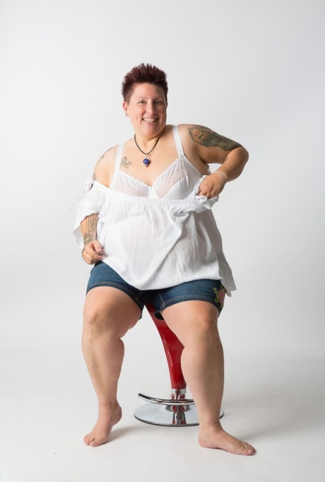 Unclothed but comfortable: This tattoo girl is sitting on a stool after getting naked.