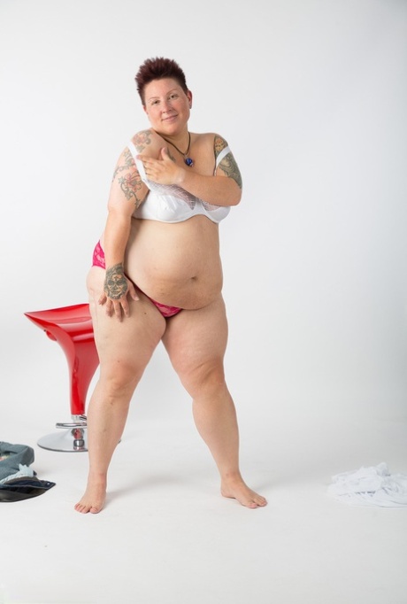 Tattoo girl, who is an elderly and unwell tattoo artist, gets completely naked and sits on a stool.