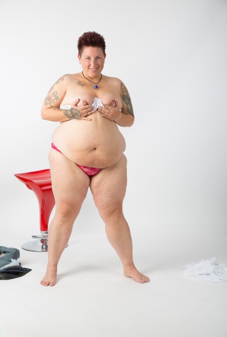An overweight amateur tattoo artist gets into a semi-naked state and sits on top of a stool.