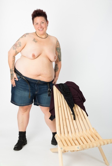 An overweight tattoo artist, who is a self-sufficient tattoo artist, removes herself and her clothes by stripping down to her