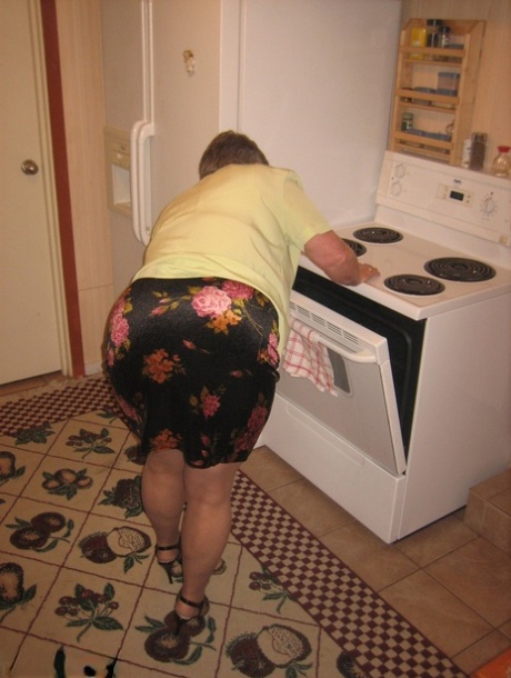 In her kitchen, the Girdle Goddess, an elderly woman, exposes herself to pantyhose.