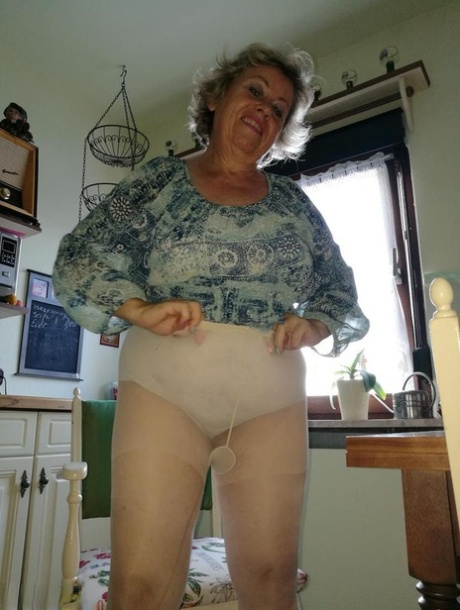 The hairy granny Caro clings to her banana while in her natural pussy on the kitchen chair.