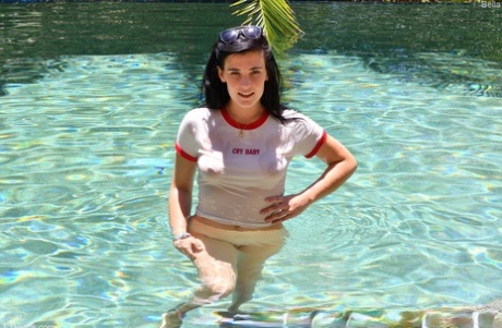 A young woman with dark hair takes a dip and then displays her exposed buttocks in a swimming pool.