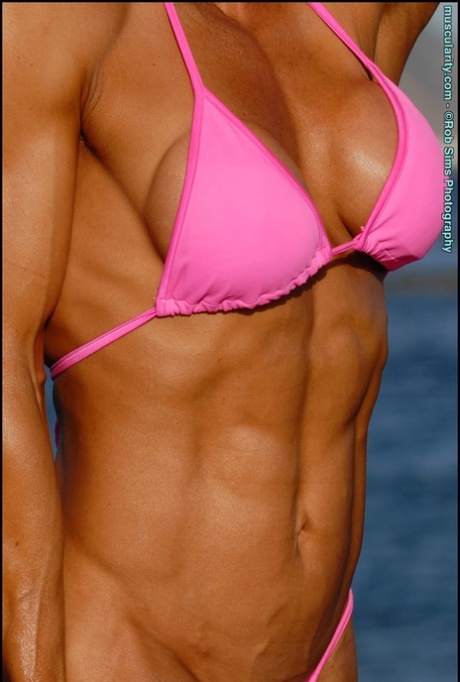 In a beach setting, Jennifer Dejoya, an Asian bodybuilder, is seen wearing a pink bikini.