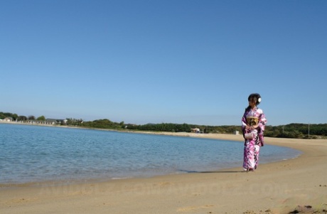 The beach and surrounding area witness the arrival of Chiaki, a beautiful Asian model, dressed in a kimono as she strolls along.