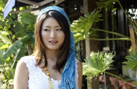 A white dress-clad Asian girl walks into the ocean to her knees.