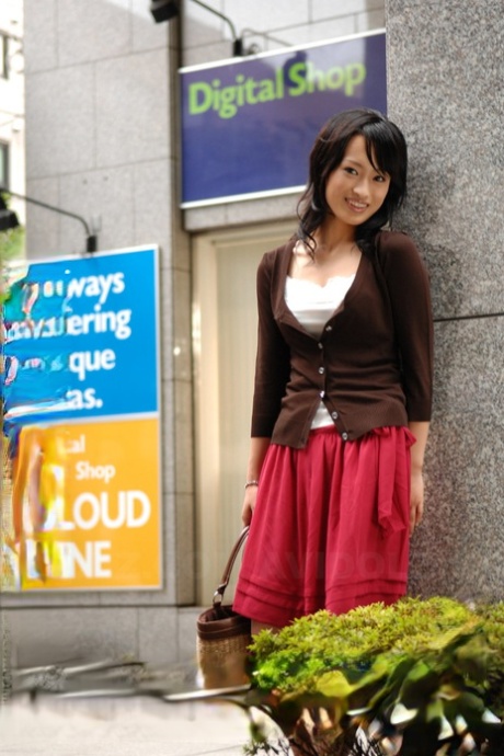 In a skirt that falls to her knees, Mio Kanna, a Japanese beauty, strolls through the downtown area.