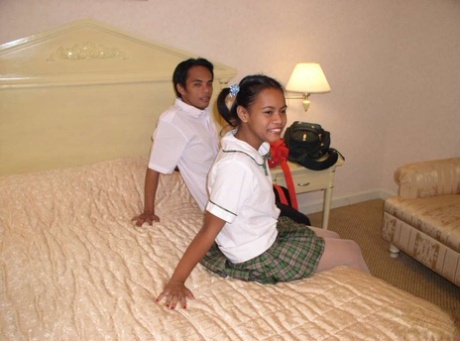 The innocent appearance of an Asian schoolgirl on her parent's bed is accompanied by her naked facial expression.