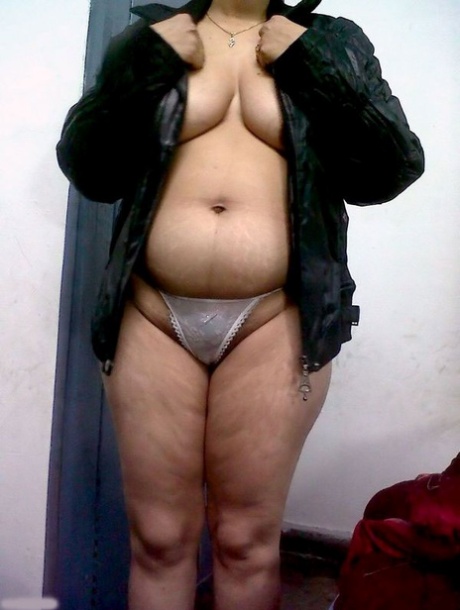Wearing a bra and thongs, a fat Indian woman conceals her face.