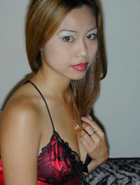 While modeling in the nude, a petite Asian woman with strong breasts slips off her satin lingerie.