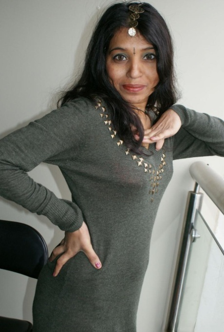 The Indian woman, Kavya Sharma, removes her clothes and boots before sitting on a cushion.