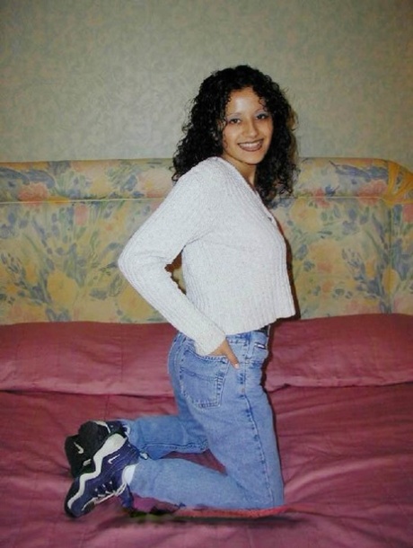 Curly haired Latina exposes her bare ass on top of the bed.