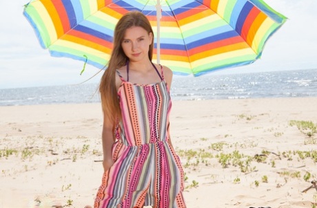 Beautiful young girl Dominika gets totally naked under an umbrella on a beach