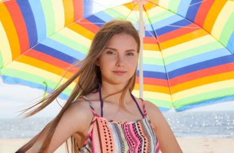 Beautiful young girl Dominika gets totally naked under an umbrella on a beach