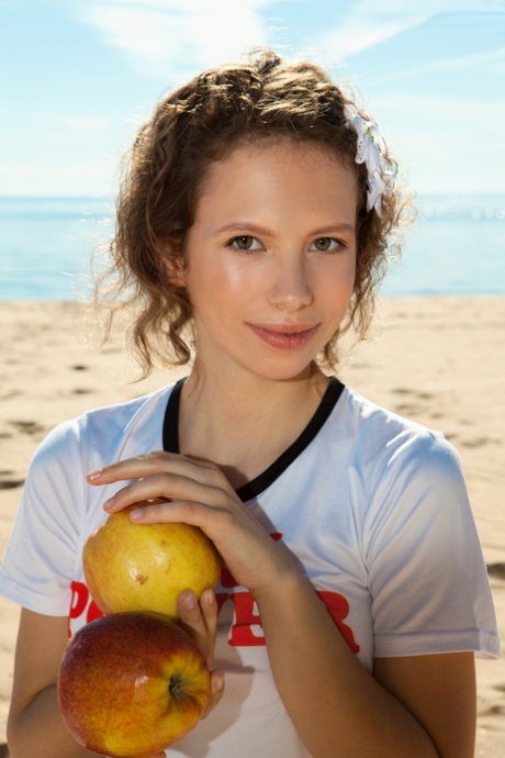 Young-looking Amore is seen naked on a sandy beach.