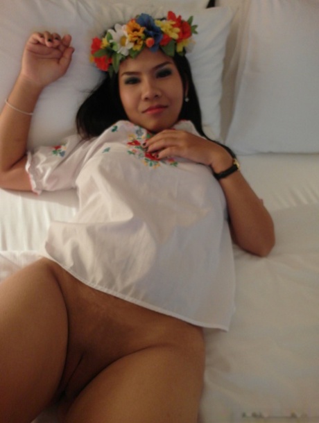 Asian amateur Aziza wears a crown of flowers and performs oral sexual acts on her anus.