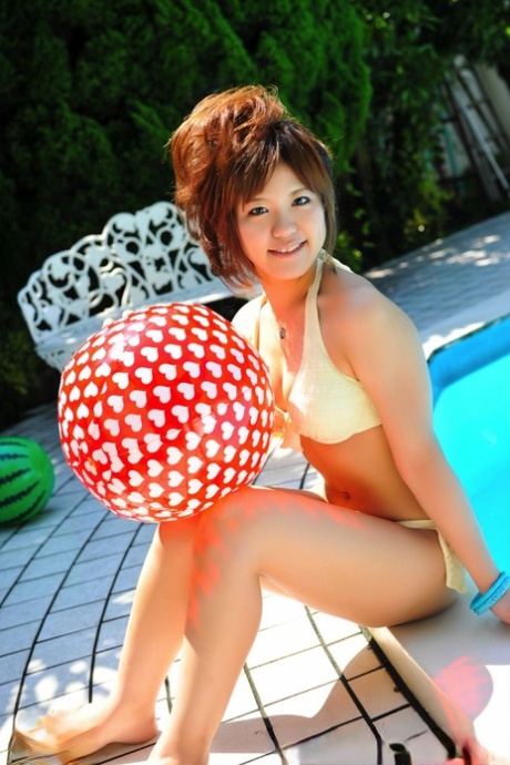 Japanese redhead models a white bikini and holds two balls.