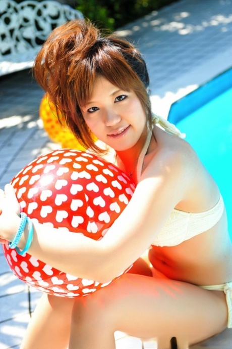 Japanese redhead models themselves wearing white bikinis while holding a couple of balls.