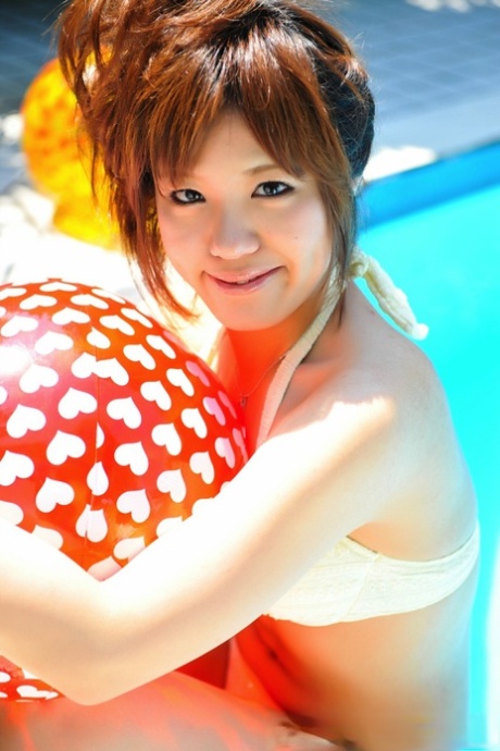 While modeling a white bikini, the Japanese redhead holds onto two balls.