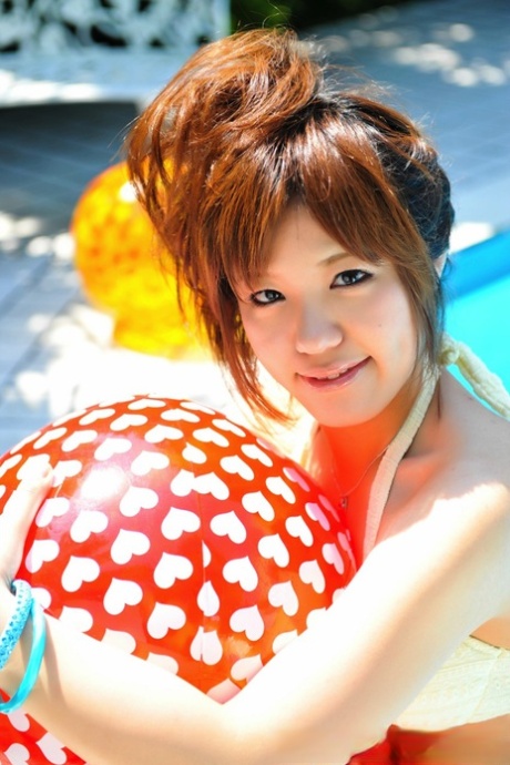 While modelling a white bikini, the Japanese redhead is holding onto two balls.