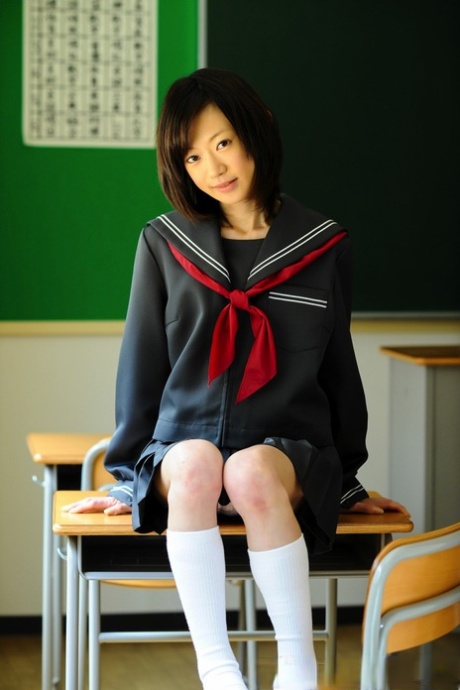 A Japanese student in a barely legal state displays her knees unadorned in her school uniform.