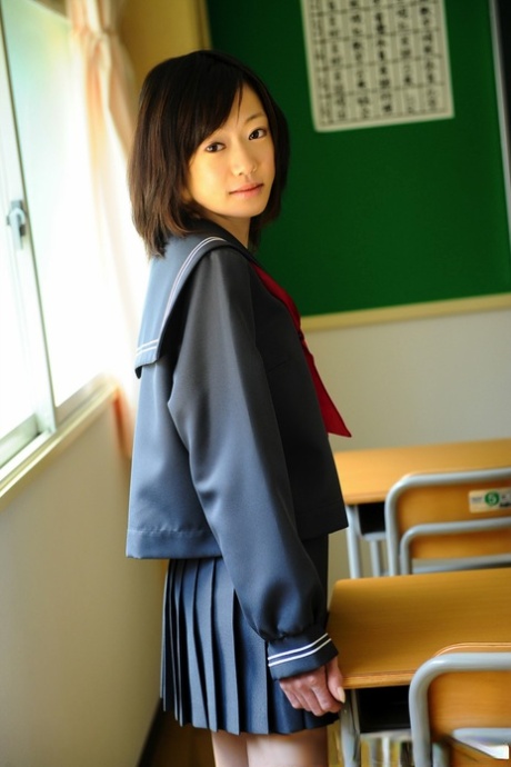 A Japanese high school student who is not legally bound exhibits her knees without any clothing in her school uniform.