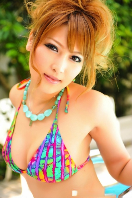 Splendid japanese redhead poses in a bikini by the side of a pool.