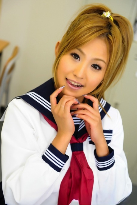 Posing in her uniform, the charming Japanese student with a striking appearance sits on a bench.