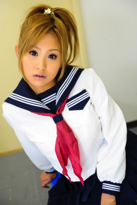 The beautiful-looking Japanese student looks adorable sitting on a bench in uniform.